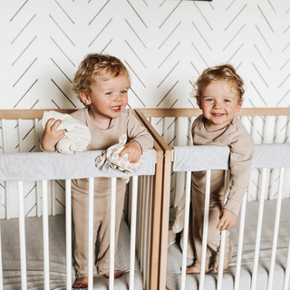 two toddlers in cot with teething rails attached